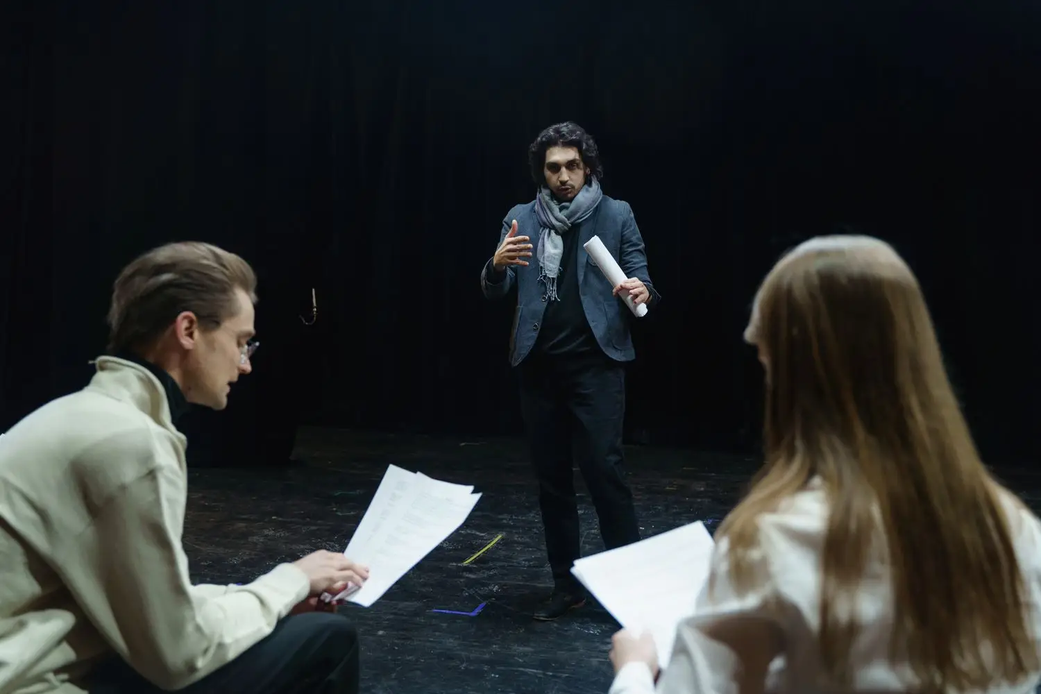 Actors and a director discussing a script in rehearsal